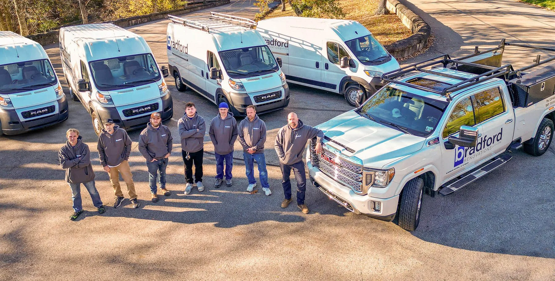 The Bradford Renovations crew standing with their branded trucks and vans