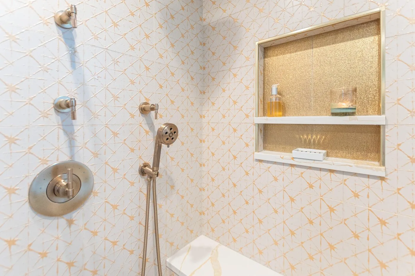 Tiled shower niche with a brass shelf and patterned surround