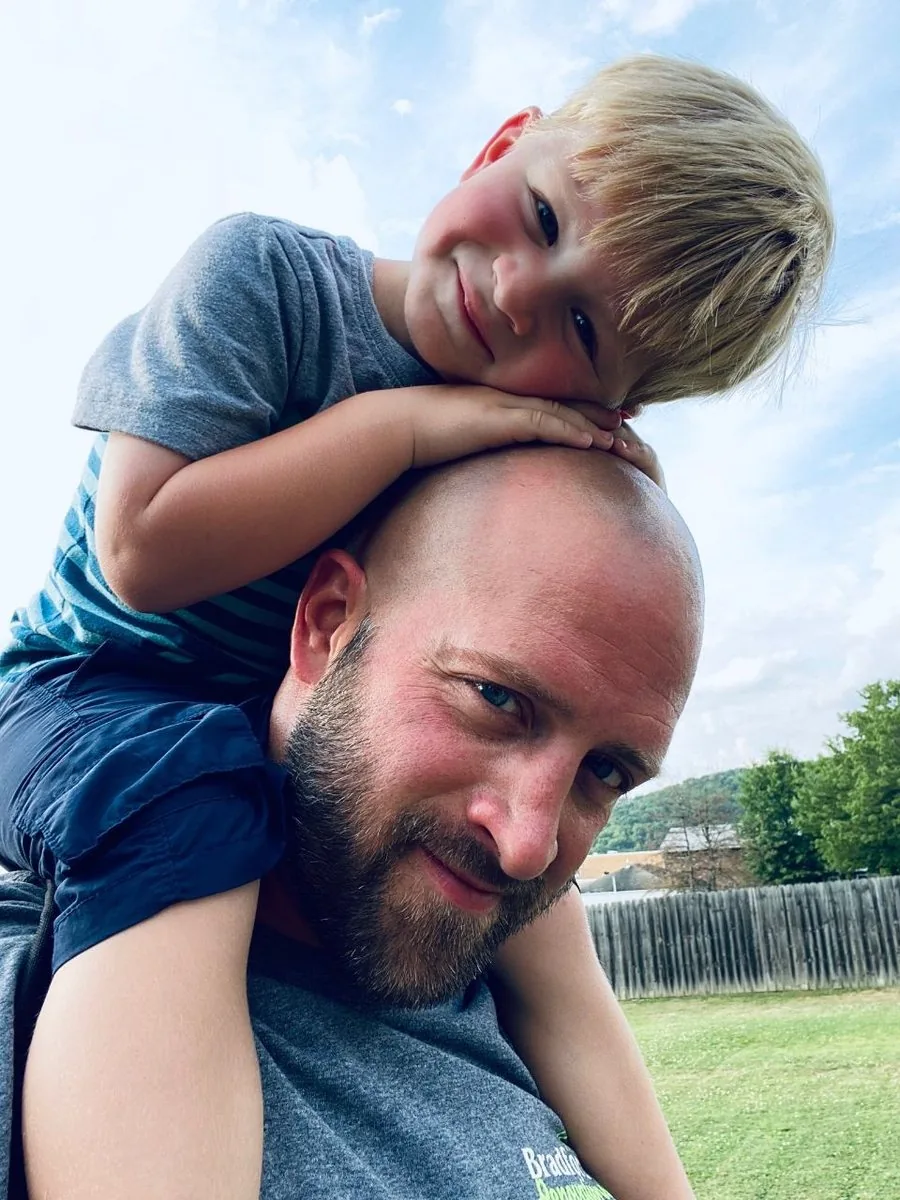 Drew Bradford outside with his son on his shoulders