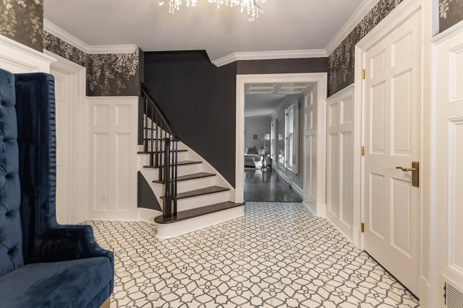 Entry hall with a patterned tile floor, painted stair and dark trim