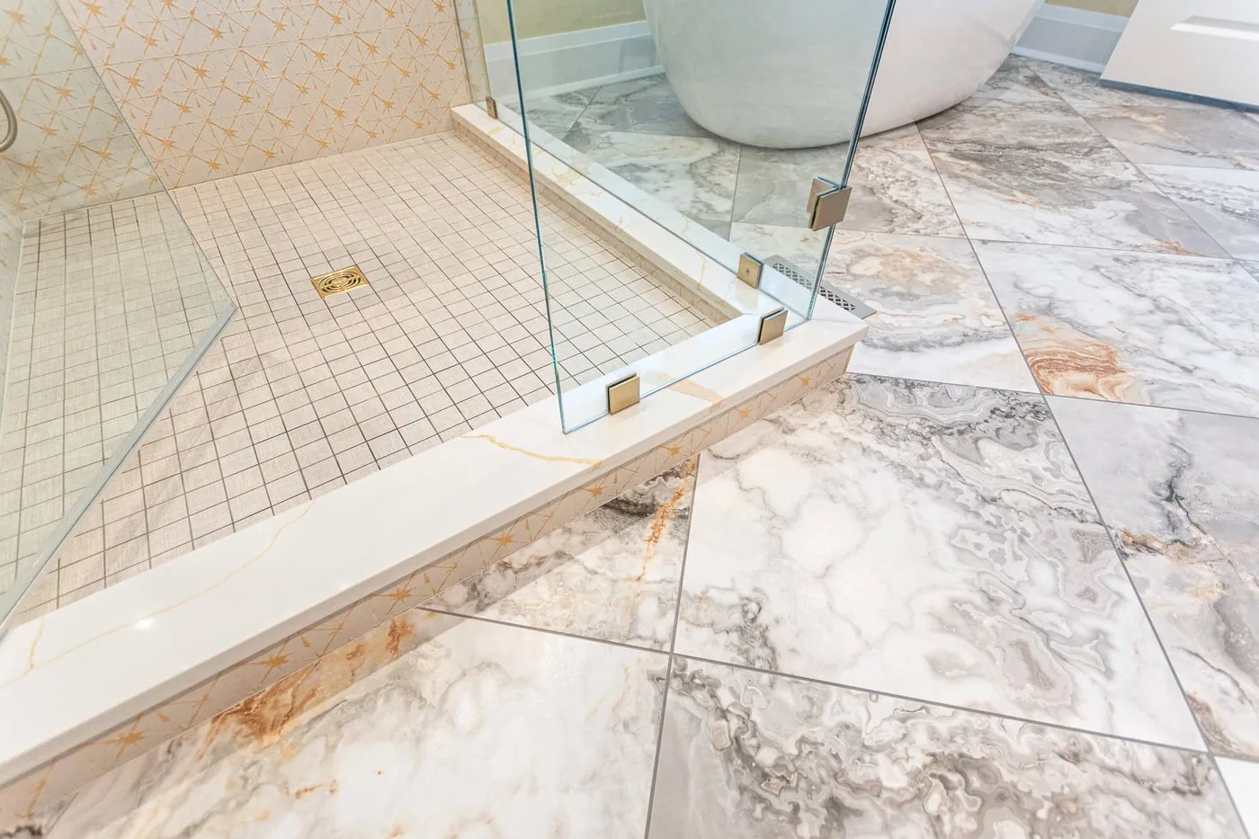 Marble shower floor meeting a frameless glass panel