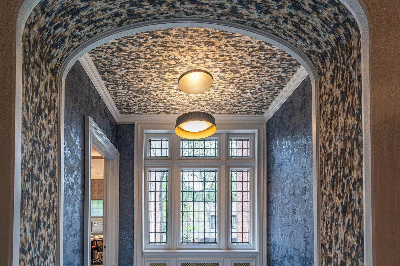 Arched alcove with patterned wallpaper and a pendant light